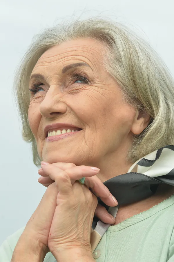 Hot-Flashes-and-Night-Sweats-Treatments An older woman holds her hands together under her chin and looks up at a cool sky smiling. Get treatment for hot flashes and night sweats from Richard Conlen, MD, FACOG in Boca Raton.