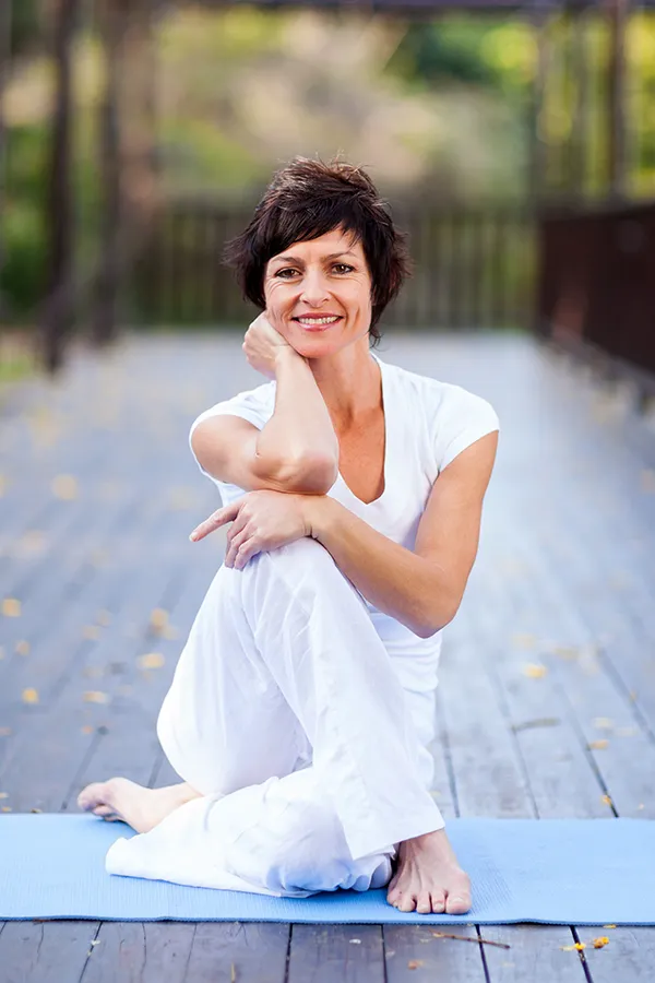 Osteoporosis-Treatment A middle-aged woman happily sits in a yoga pose. Get Osteoporosis treatment from Richard Conlen, MD, FACOG in Boca Raton.