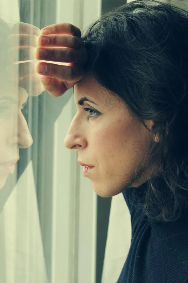 PCOS-Treatment A brunette woman in a thin dark turtleneck looks out the window with a serious expression, suffering from PCOS. Get treatment for Polycistic Ovarian Syndrome/PCOS from Richard Conlen, MD, FACOG in Boca Raton.