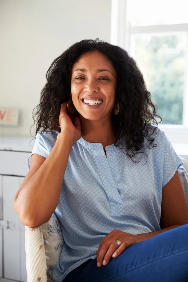 PIR-Insulin-Resensitization-Treatment A middle-aged black woman in blue-toned clothes sitting and smiling in a sunlit room. Get PIR Insulin Resensitization Therapy from Richard Conlen, MD, FACOG in Boca Raton.