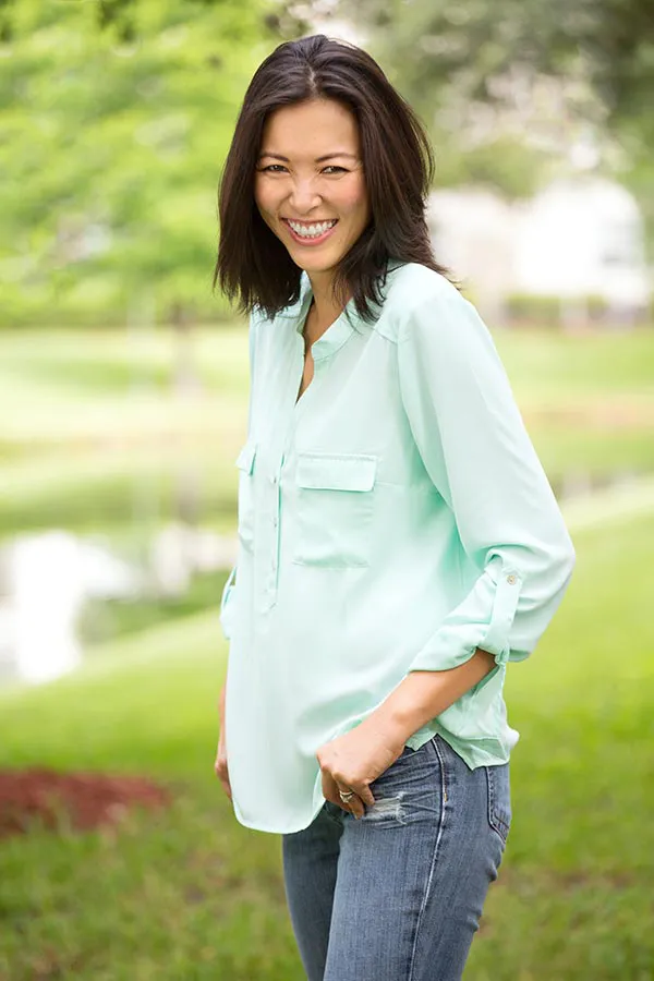 Perimenopause-Treatment A middle-aged brunette woman in a light green button-up shirt stands outside smiling, happy with her perimenopause treatment from Richard Conlen, MD, FACOG in Boca Raton.