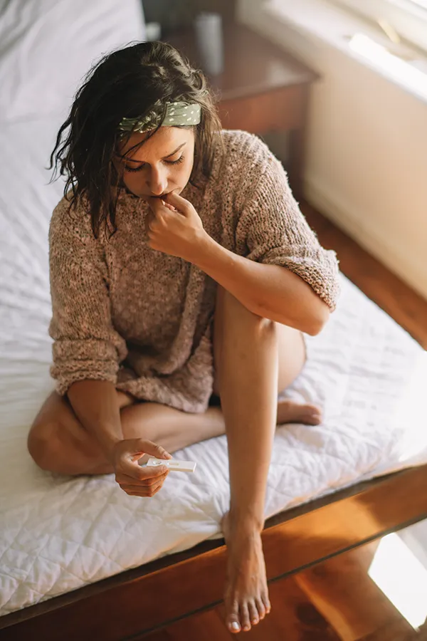 infertility-doctor A woman waits for the results of a pregnancy test on her bed. Get infertility treatment from Richard Conlen, MD, FACOG in Boca Raton.