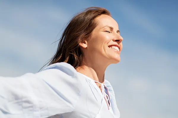 well-woman-exam A woman closes her eyes and opens her arms in the sunlight and blue sky. Get a well woman exam from Richard Conlen, MD, FACOG in Boca Raton.
