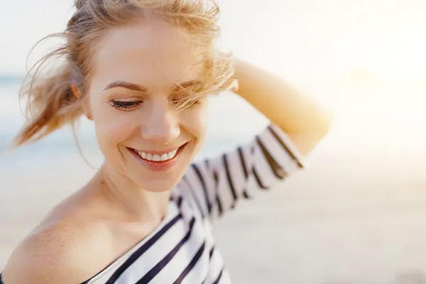 womens-health-doctor A woman in a striped shirt smiles and runs her fingers through her hair in the sunshine. Schedule women's health treatments from Richard Conlen, MD, FACOG in Boca Raton.